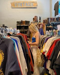 a woman standing in front of a rack of clothing and looking at the items on display