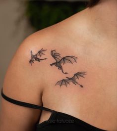 a woman's back shoulder with three flying bats tattoo on her left upper arm