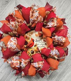 an orange and red wreath with autumn decorations