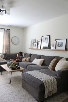 a person sitting on a couch in a living room next to a coffee table and window