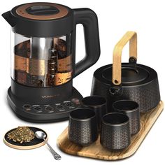 an electric tea kettle with four cups and spoons