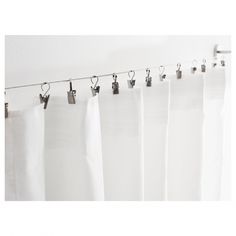 white curtains hanging on a line in front of a wall with hooks attached to it