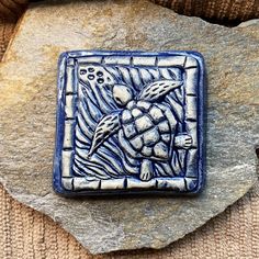 a blue and white tile with an image of a sea turtle on it's back