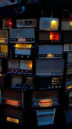 many old radio's are stacked on top of each other in this dark room