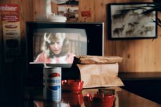 a can of pepsi sitting on top of a table in front of a flat screen tv