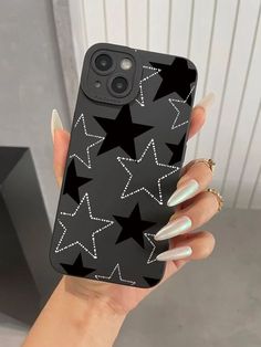 a woman's hand holding an iphone case with black stars on the back and white nails