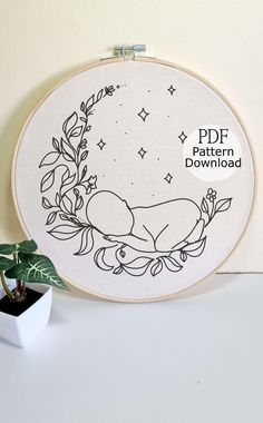 the embroidery pattern is being displayed next to a potted plant