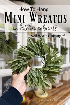 a person holding a plant with the words how to hang mini wreaths on kitchen cabinets without damage