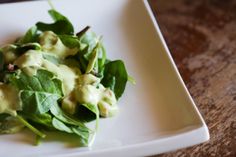 a white plate topped with salad on top of a wooden table