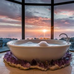 a large white bath tub sitting inside of a bathroom next to a tall glass window