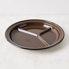 an empty brown plate on a white countertop with a knife and fork sticking out of it