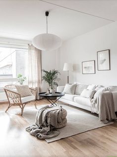 a living room filled with furniture and a large white rug on top of a hard wood floor