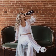 a woman sitting on a couch drinking from a bottle