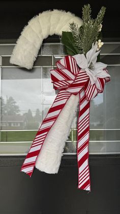 a christmas wreath hanging on the front door decorated with candy canes and greenery