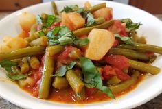 a white plate topped with green beans and potatoes