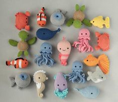 crocheted sea animals are arranged in a circle on a gray surface, including an octopus, fish, and other marine creatures