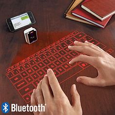 a person using a mouse and keyboard on a wooden table with various electronic gadgets