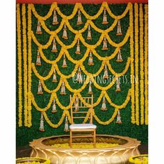 a chair sitting in front of a green wall with yellow flowers and chains hanging from it