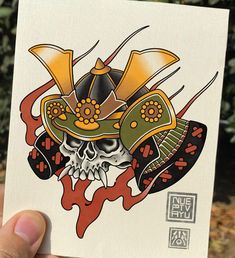 a hand holding up a sticker with a skull wearing a hat