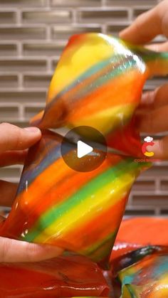 someone is holding a colorful bird made out of candy wrappers and then touching it with their hands