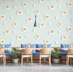 a restaurant with blue chairs and wooden tables in front of a wall with eggs painted on it