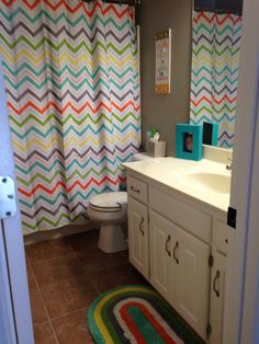 a bathroom with a colorful shower curtain and rug