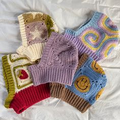 four knitted hats laying on top of a white bed sheet covered in crochet