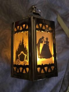 a lamp that is on top of a bed with a blue sheet behind it and the silhouettes of two people holding hands