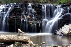 a large waterfall with water cascading down it's sides and rocks in the foreground