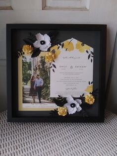 a black frame with yellow and white flowers on it next to a photo in front of a door