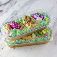 two plastic containers filled with easter treats on top of a marble countertop next to each other