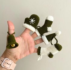 a hand is holding three crocheted christmas decorations