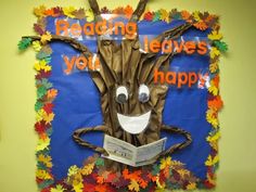 a bulletin board with leaves on it that says reading leaves you happy, and a tree made out of newspaper strips