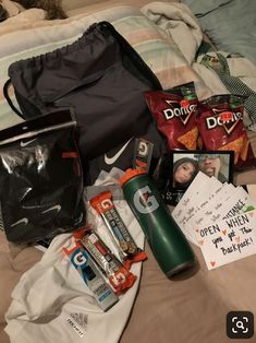 the contents of a duffel bag laid out on top of a bed next to some snacks