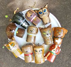 a white plate topped with lots of wooden cats on top of a cement floor covered in leaves