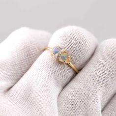 a woman's hand wearing a yellow gold ring with an opal stone in the center