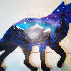 an image of a horse made out of perler beads on a wooden background with space and stars in the sky