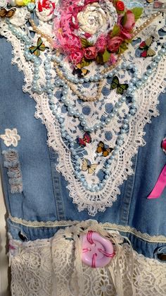 a dress made out of old jeans with lace and flowers on the bottom, along with pink ribbon