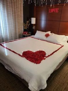 a bed with white sheets and red flowers on the headboard, in a hotel room