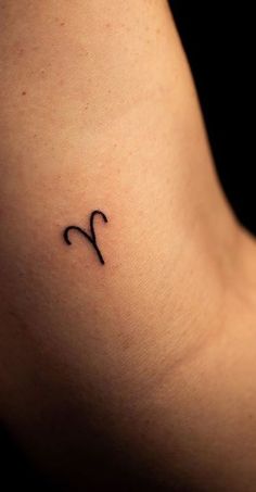 a woman's upper arm with a small zodiac sign tattoo on her left side