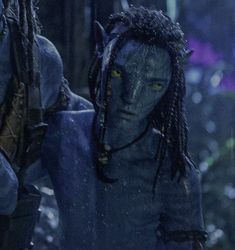 two people with dreadlocks are walking through the woods in alien costumes, one is staring at the camera