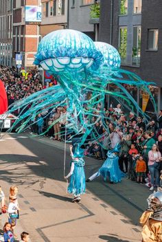 a parade float in the middle of a city street with people watching and taking pictures