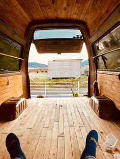 someone's feet in the back of a truck with wood flooring and windows