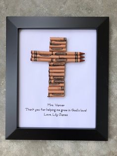 a cross made out of crayons in a frame