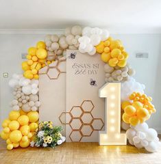 a number one balloon arch with balloons and flowers on the floor in front of it