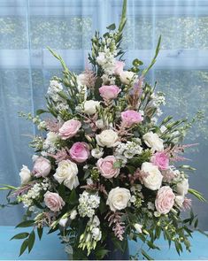 a vase filled with pink and white flowers on top of a blue table next to a window