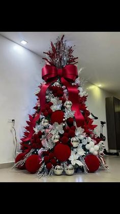 a red and silver christmas tree with ornaments on it's base, in a room