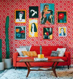 a living room with red couches and pictures on the wall above them, along with cacti and succulents