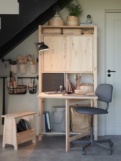 a home office under the stairs with baskets and other items on it's shelves