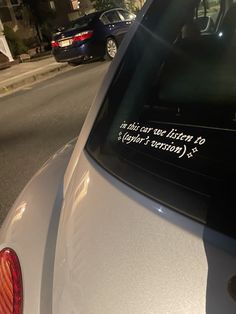 a car parked on the side of the road with writing on it's rear window